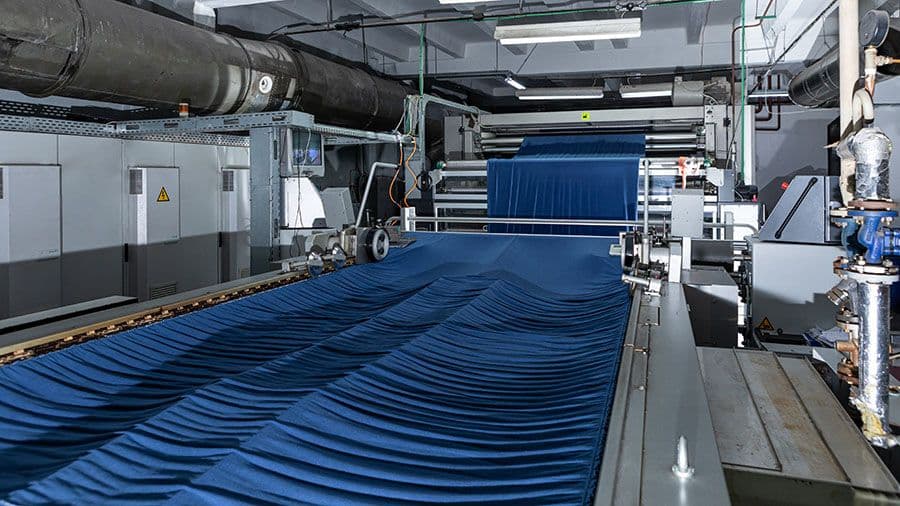 Blue fabric running through a finishing machine